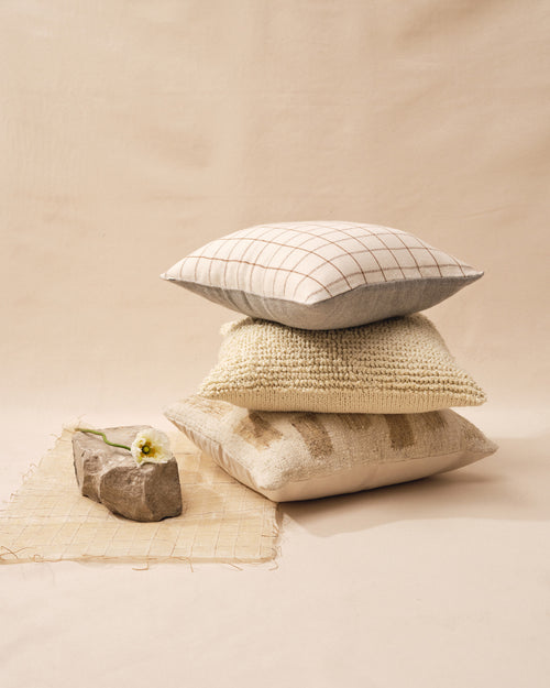 A stack of three neutrally colored ethically made MINNA decorative throw pillows.