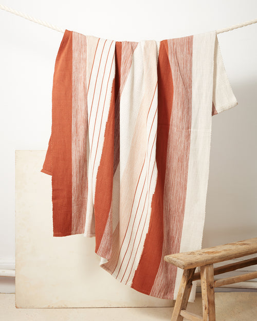 Ethically handwoven cotton throw blanket with rust, orange, and cream stripes, backstrap loom
