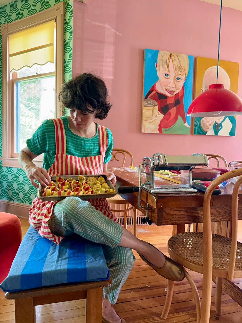 Audrey Leary (@homerunballerina)in her colorful kitchen wearing the MINNA Utility Apron in Hibiscus