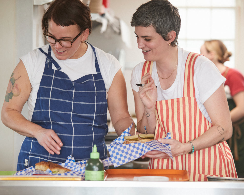 In Community with: Quinn Rose Levine and Amy Hess from Quinnie’s of the Hudson Valley wearing the MINNA Grid Apron in Indigo and the MINNA Utility Apron in Hibiscus
