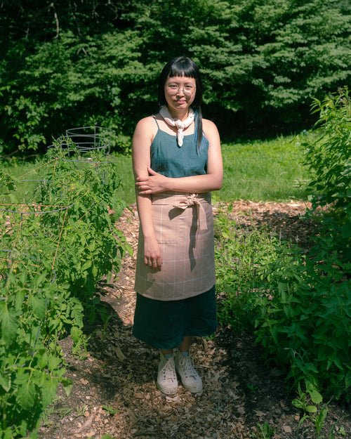 A person wearing the ethically handwoven cotton MINNA bistro apron in peach, pink.
