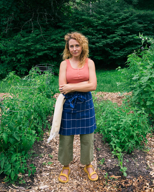 A person wearing the ethically handwoven cotton MINNA bistro apron in dark blue.