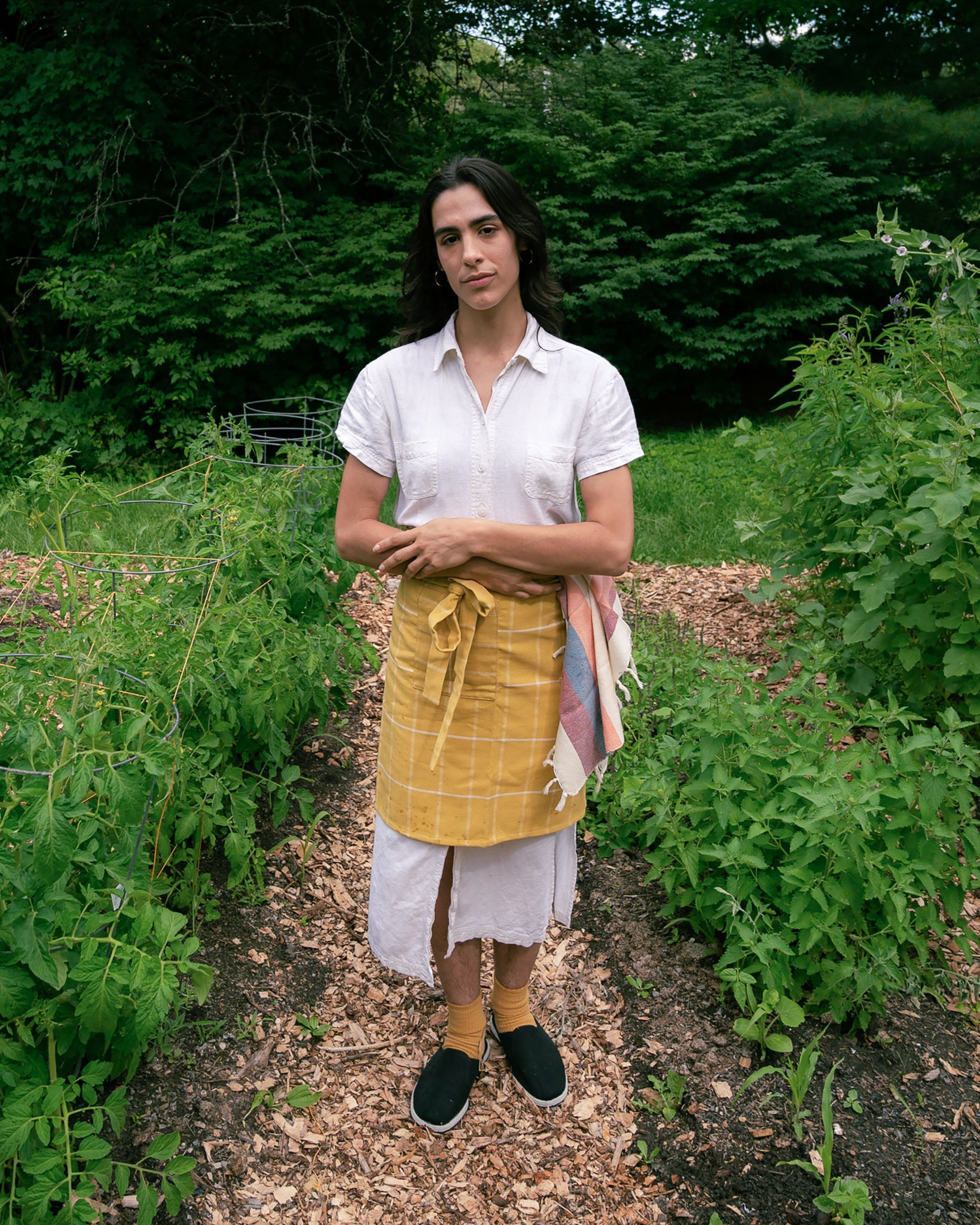 A person wearing the ethically handwoven cotton MINNA bistro apron in golden yellow.