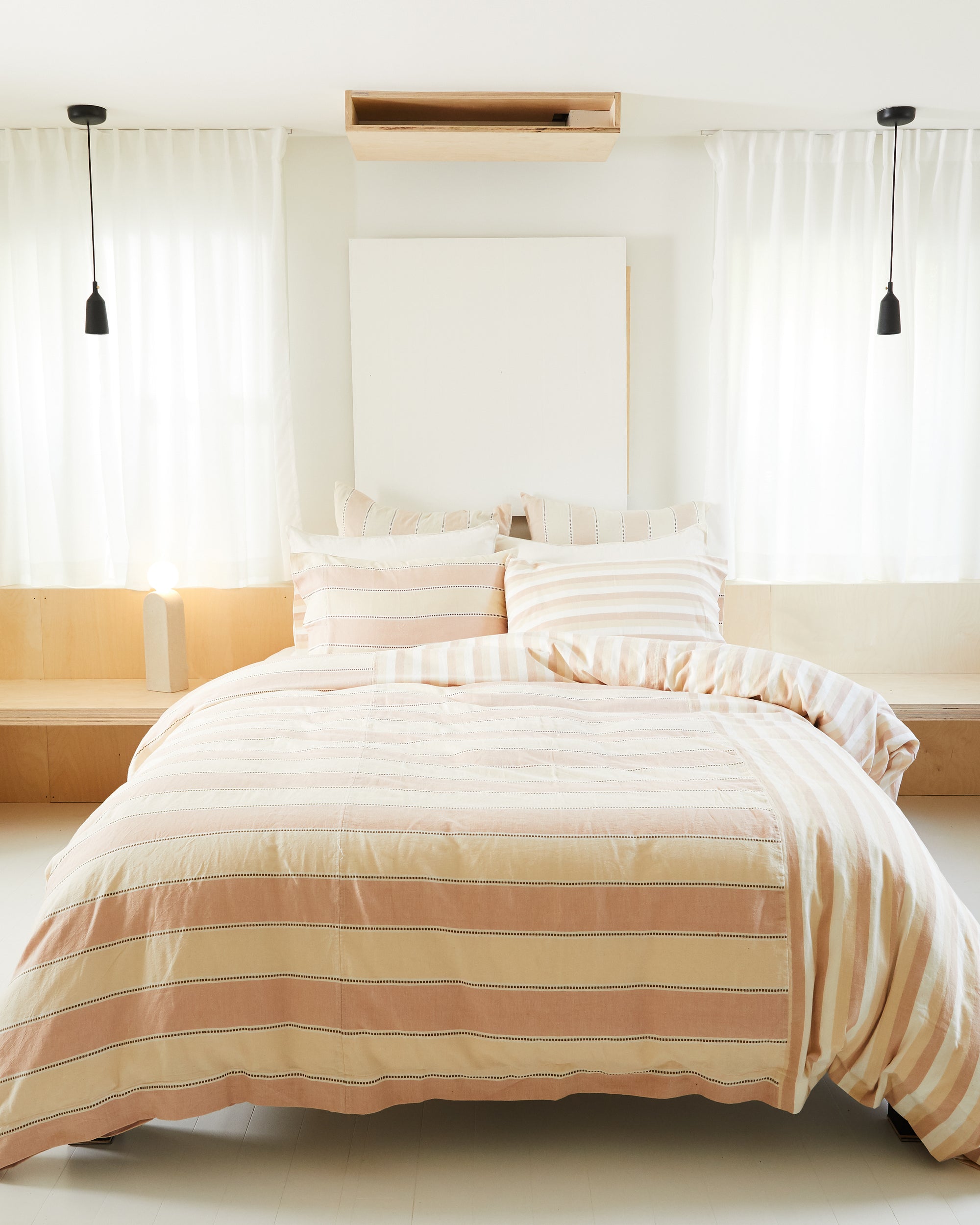 Bright bedroom with ethically handwoven oeko-tex cotton bedding designed by MINNA in peach terracotta clay colored neutral stripes