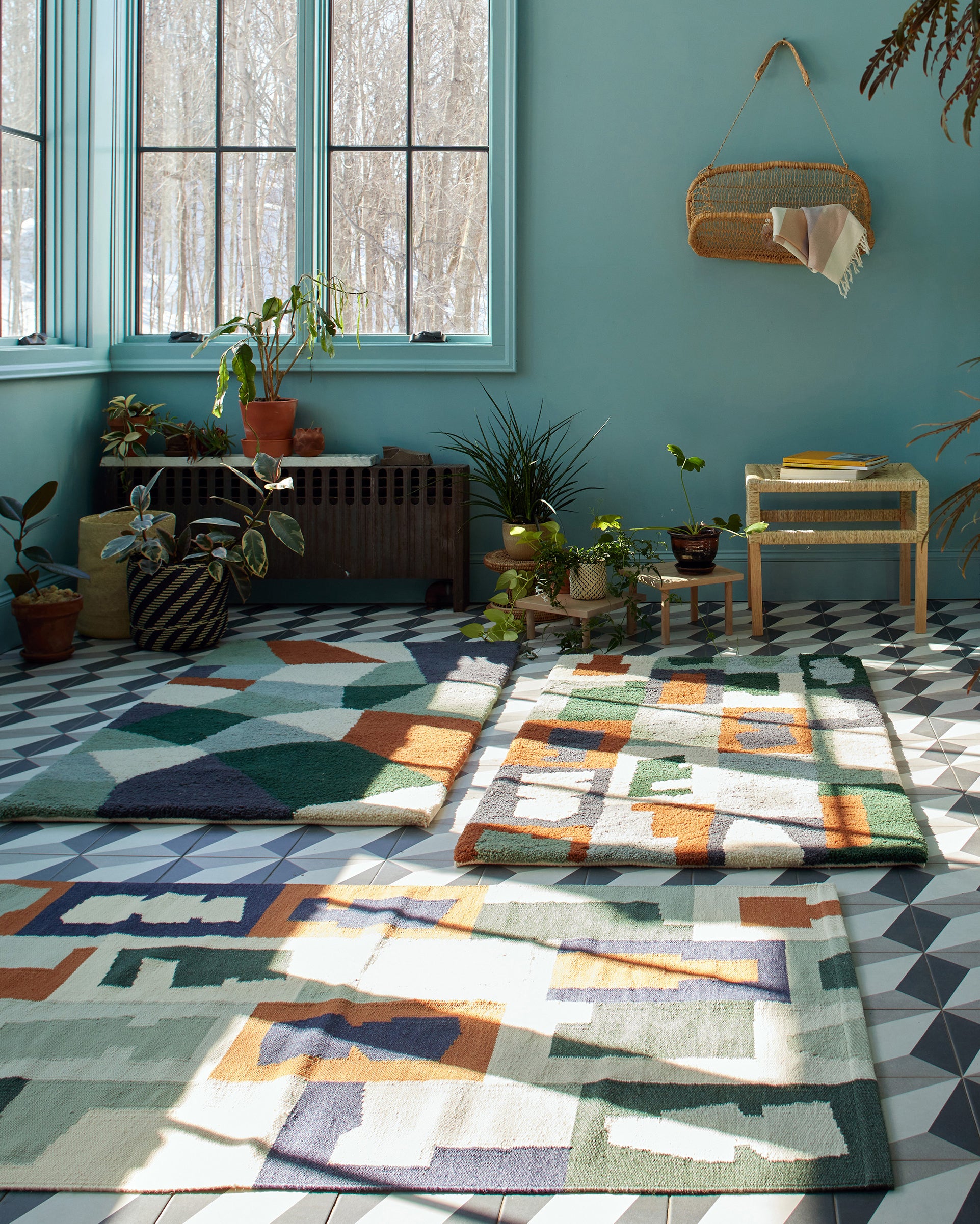 A blue room with graphic tile and ethically handwoven MINNA rugs with a jonote basket wall hanging.