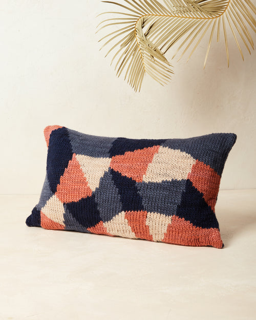 Ethically made knit graphic pillow in deep blue, peach, and coral.