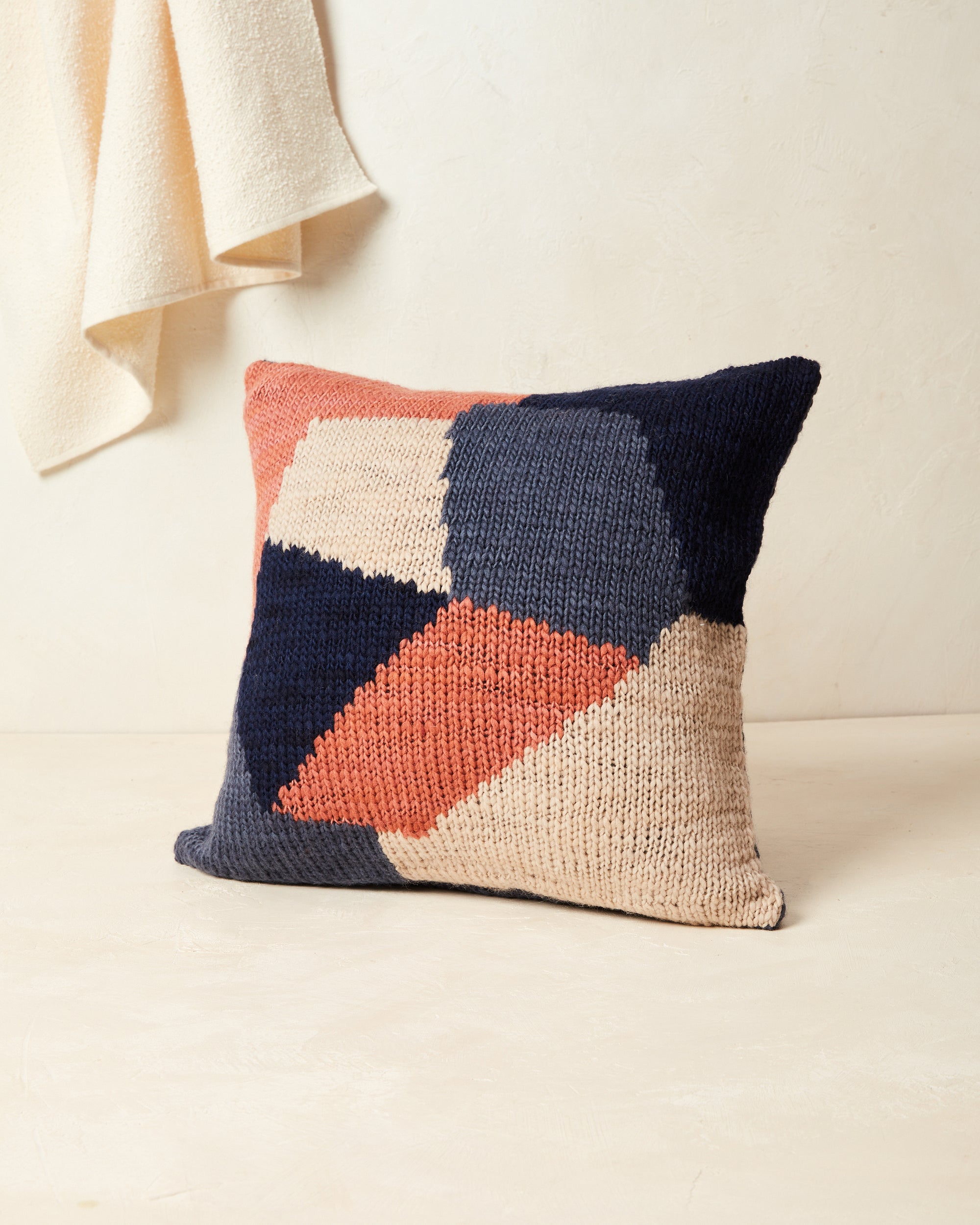 Ethically made knit graphic pillow by MINNA in dark blue, peach, and coral.