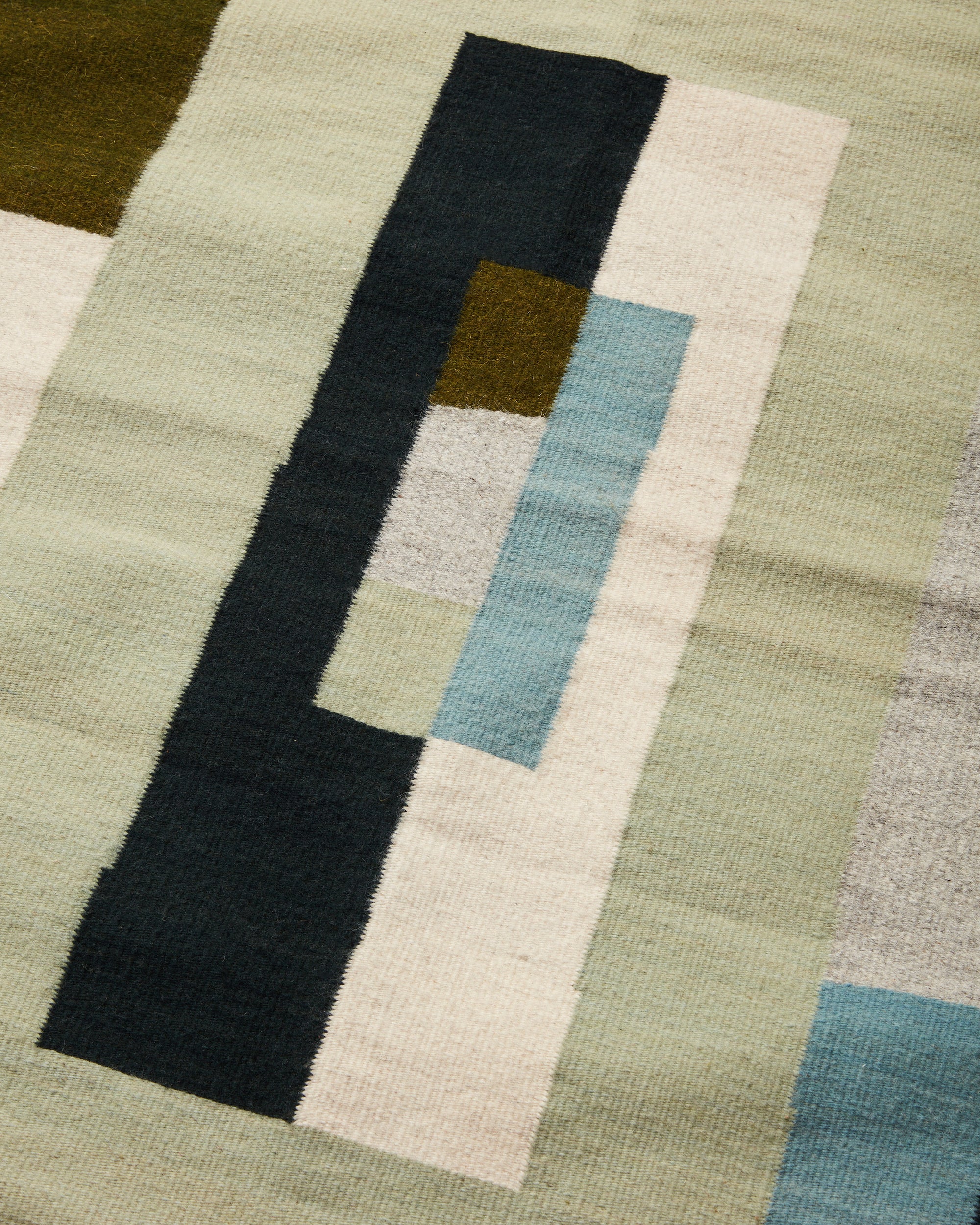 close-up of naturally dyed, ethically handwoven wool MINNA rug in shades of green.