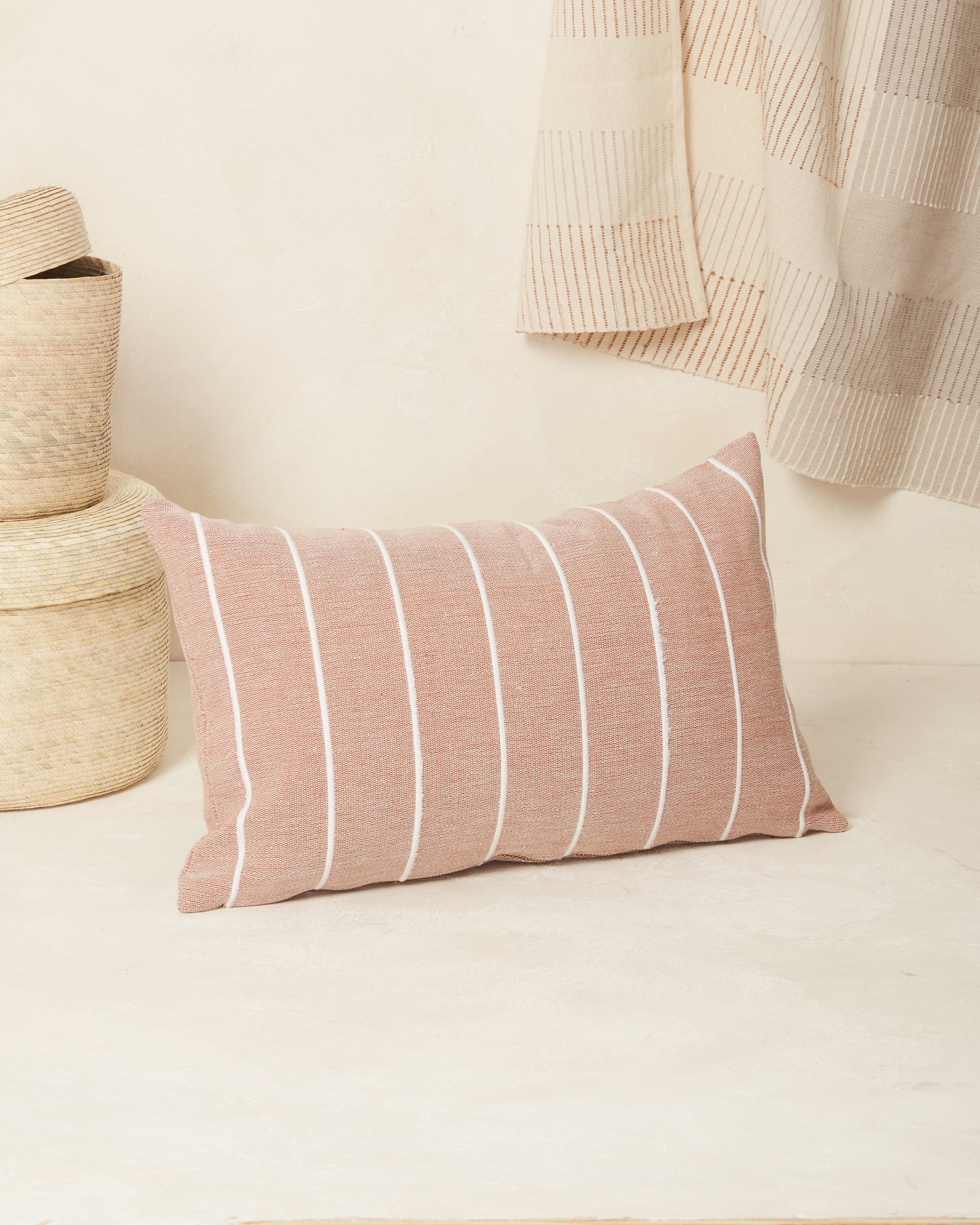 Ethically handwoven decorative MINNA throw pillow with clay and cream stripes.
