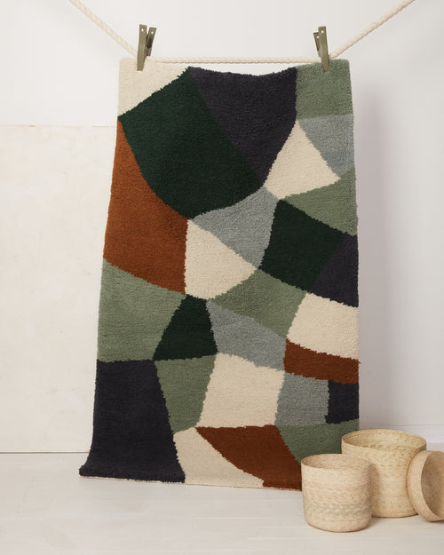 Ethically made handknotted pile rug in graphic mosaic pattern by MINNA in hunter green, cream, sage, and rust.