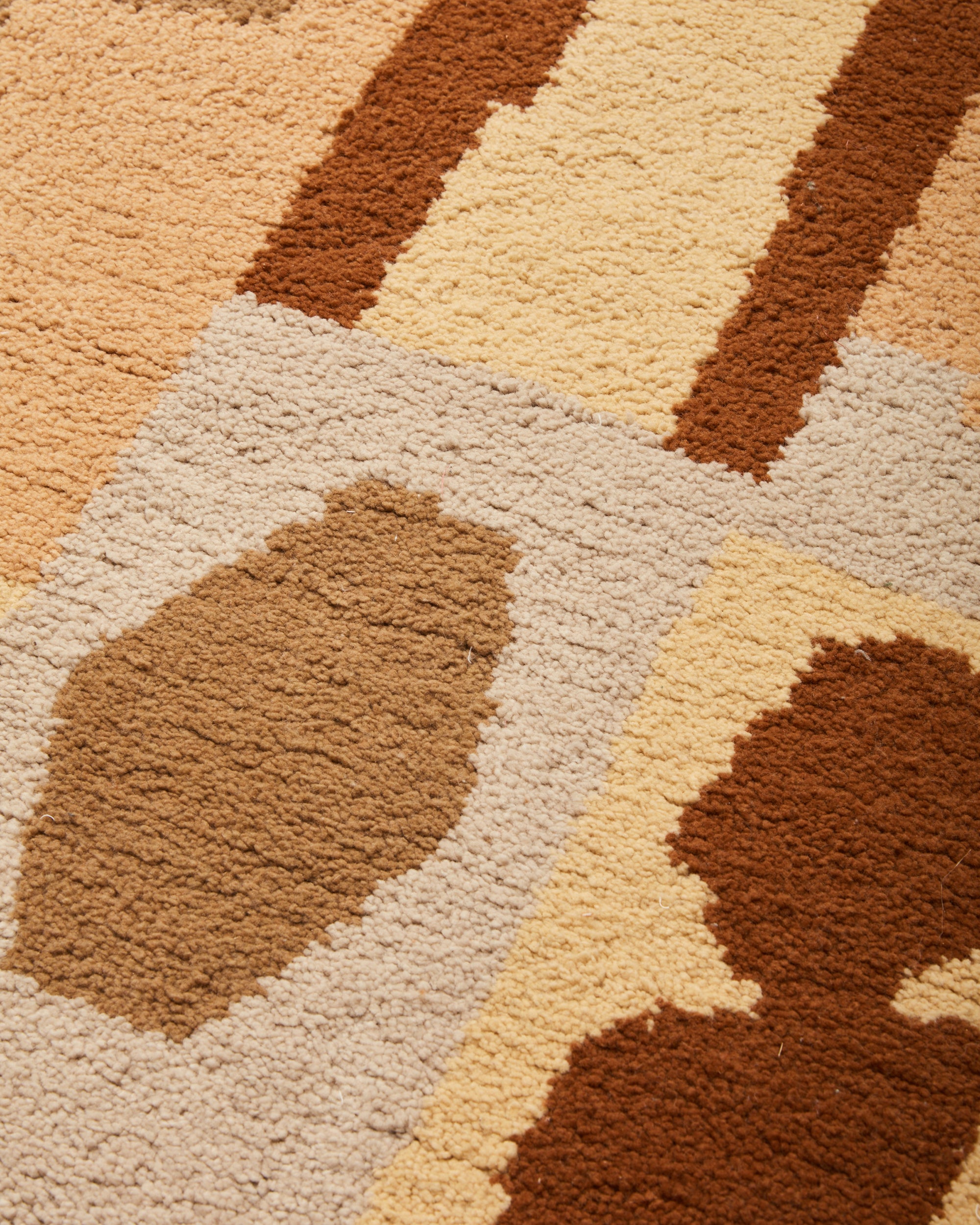 close up detail of MINNA pile handwoven shag rug with graphic shapes camel, beige, rust, cream