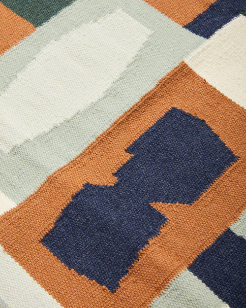 close-up of Vessels Rug Hunter by MINNA. Handwoven wool flat weave rug in graphic pattern sage green, dark blue, rust