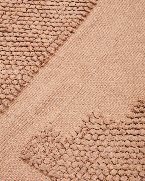 close-up detail of ethically handwoven organic cotton MINNA bathmat with textural pattern in beige, peach, neutral